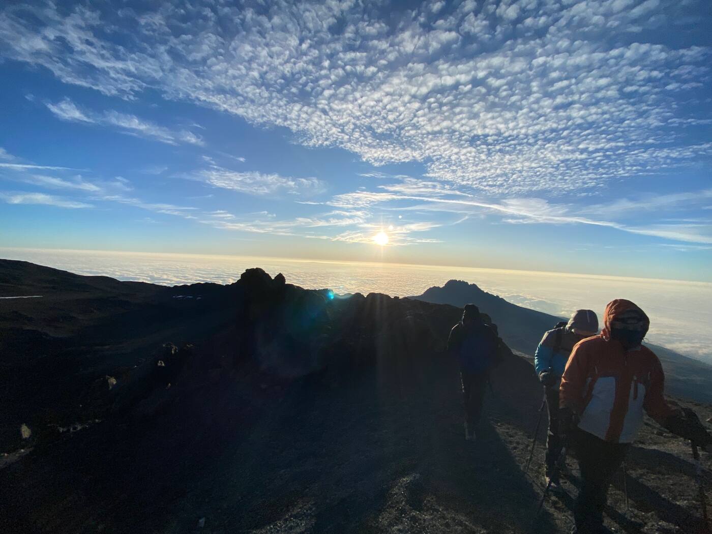 File de marcheurs au-dessus des nuages, soleil bas