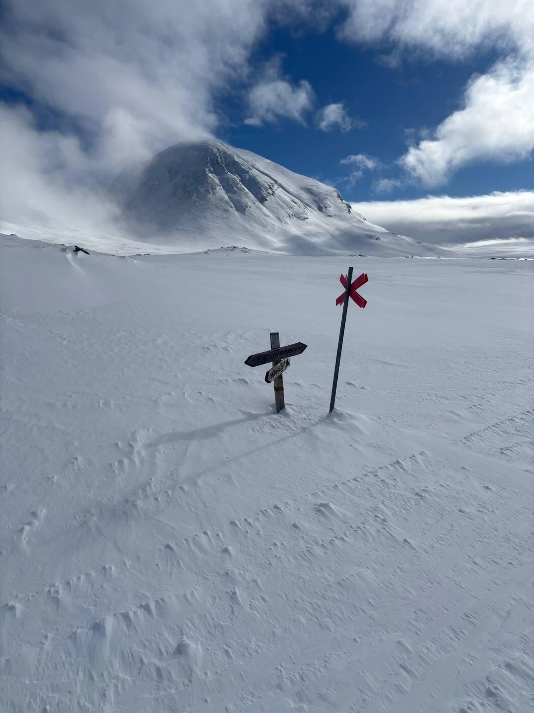 Pancarte Kungsleden et croix rouge, sommet ennuagé