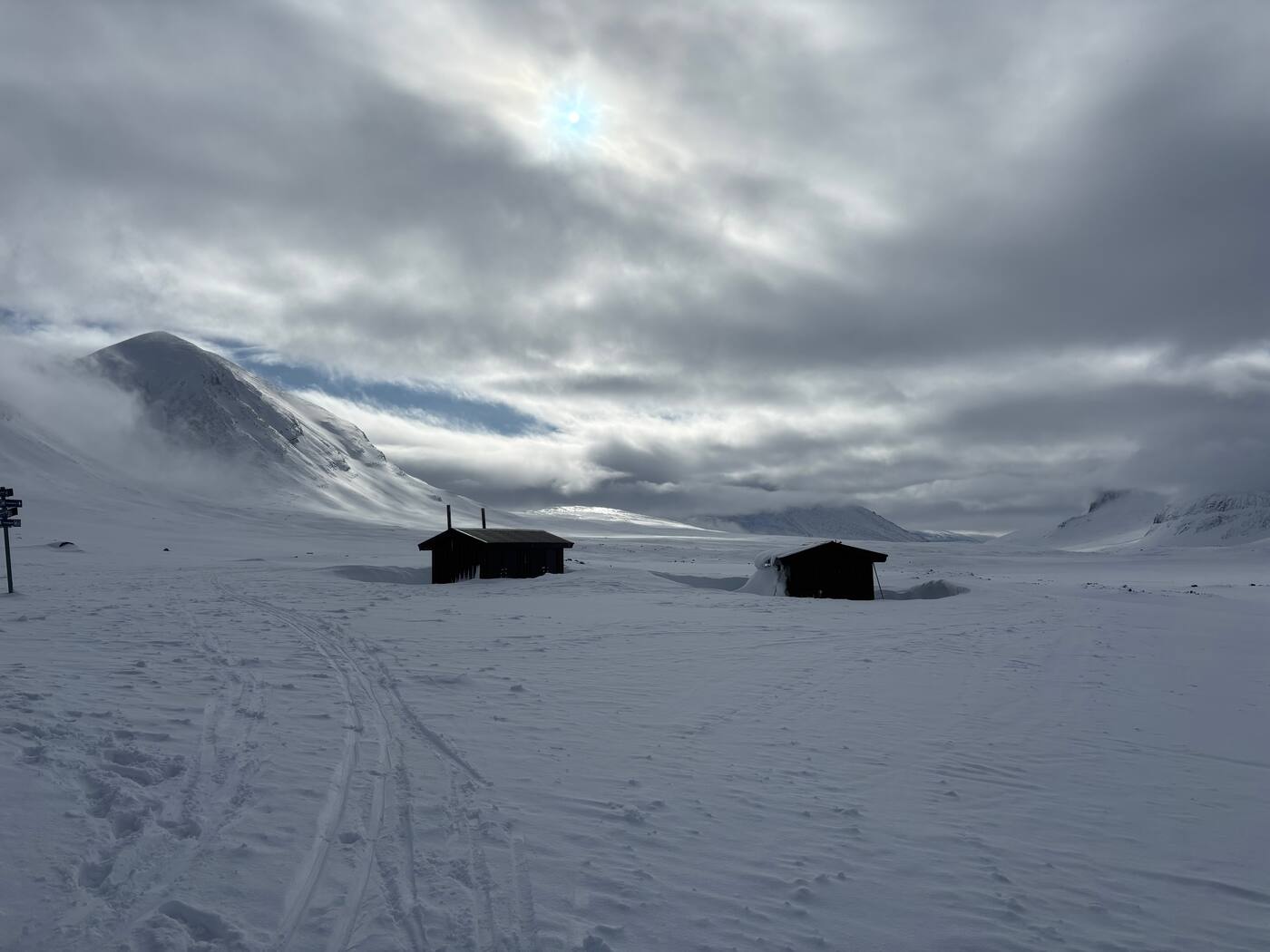 Deux cabanes noires dans la vallée, traces de ski